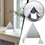 Elegant glass pyramid sculpture placed on a white windowsill, reflecting natural light and creating a modern, minimalist aesthetic.