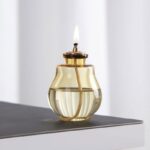 Elegant oil lamp with glass body and brass accents, perfect for home decor or educational demonstrations of traditional lighting methods.