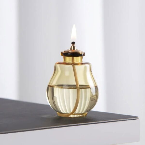 Elegant oil lamp with glass body and brass accents, perfect for home decor or educational demonstrations of traditional lighting methods.