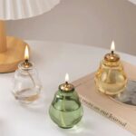 Decorative glass oil lamps with flickering flames, perfect for creating a warm and inviting atmosphere in any space. The lamps feature clear, green, and amber glass designs, adding a touch of sophisti.