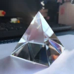 Transparent crystal pyramid with reflective surfaces, ideal for science decor and educational displays.