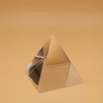 A reflective gold-colored pyramid made of metal, designed as a decorative science-themed piece or educational toy.