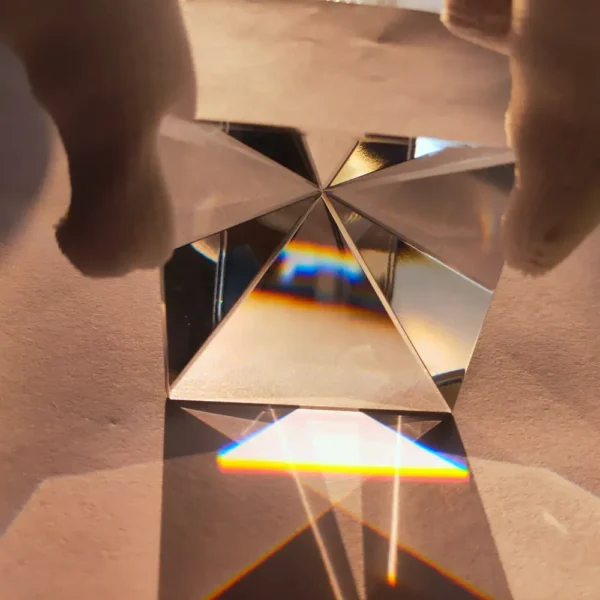 Reflective prism creating rainbow light spectrum on surface.
