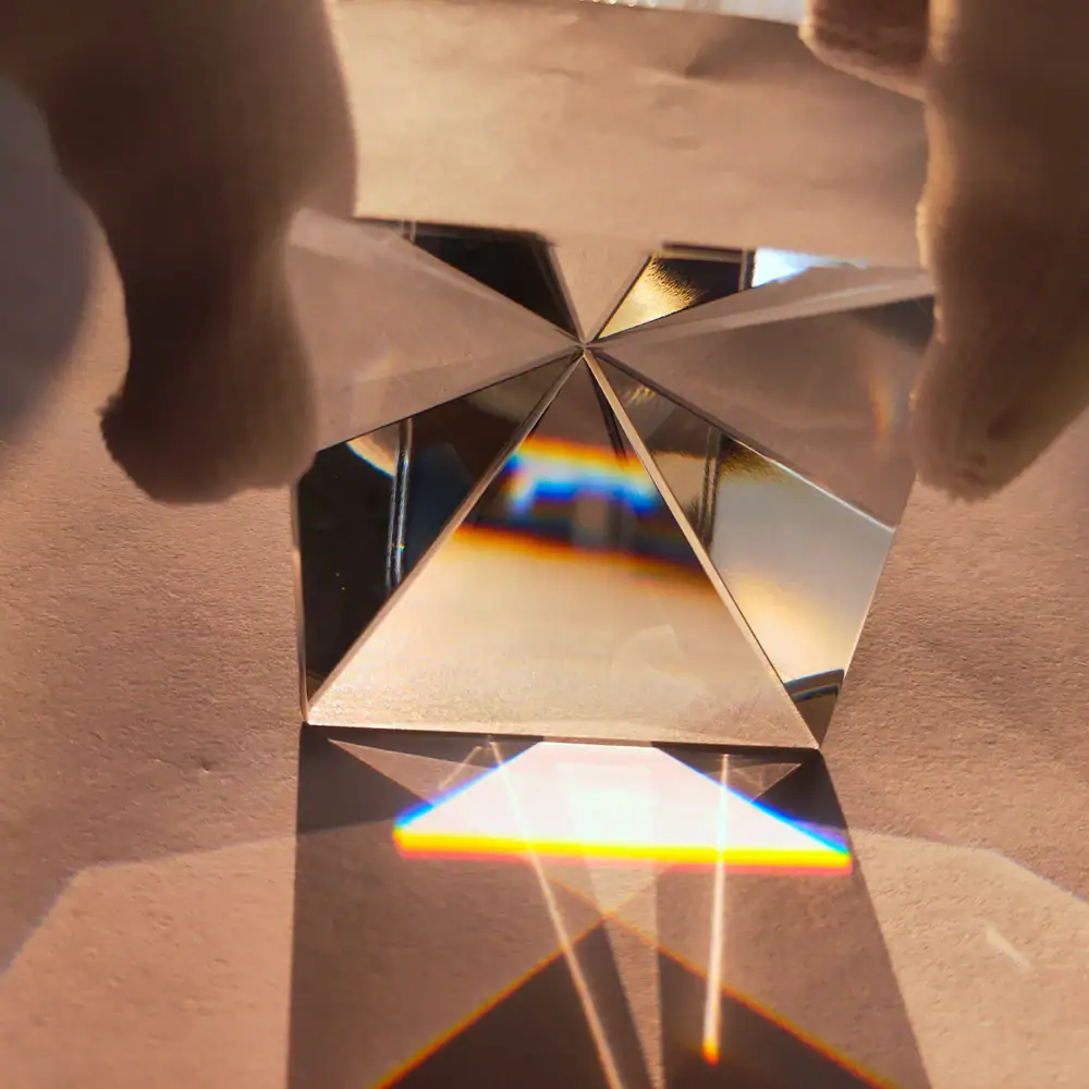 Reflective prism creating rainbow light spectrum on surface.