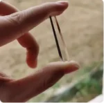 Close-up of a magnetic stirring rod held between fingers, used for laboratory mixing and scientific experiments.
