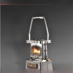 Compact portable stove with a miniature design, featuring a small fire visible through the window, ideal for camping or outdoor activities.