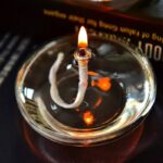 Close-up of a lit candle flame in a glass container, demonstrating combustion for educational purposes.