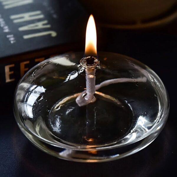 Close-up of a lit candle in a glass holder, showcasing the gentle flame and reflective surface, ideal for science decor and educational displays.