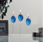 Set of three blue glass candle holders with lit candles, modern and stylish home decor accent.