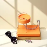 Educational magnetic ball and track science toy for kids, featuring a colorful orange and beige setup with metal balls and a power cord, ideal for STEM learning and science experiments.