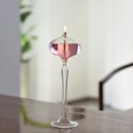Elegant glass candle holder with a lit candle, showcasing a scientific-inspired design.