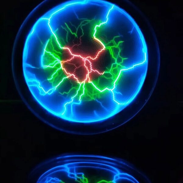 Close-up of a Tesla coil generating vibrant blue, green, and red electric sparks in a dark environment, showcasing high-voltage electrical discharge.