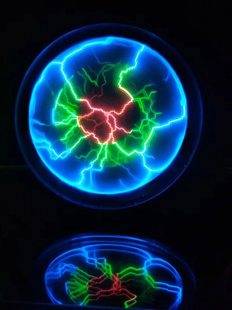 High Voltage Tesla Coil with Electric Sparks Close-up of a Tesla coil generating vibrant blue, green, and red electric sparks in a dark environment, showcasing high-voltage electrical discharge.