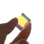 Clear glass prism demonstrating light refraction and dispersion with colorful light spectrum.