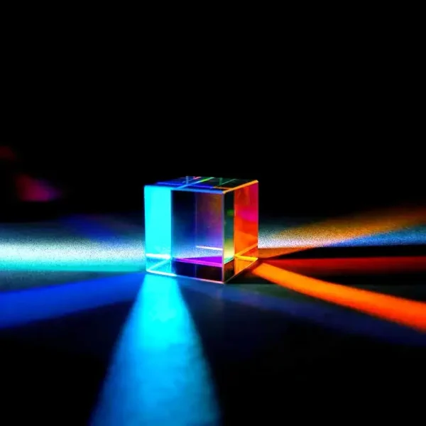 A vibrant, transparent glass prism casting multicolored light reflections and shadows on a dark surface, showcasing optical effects and light dispersion.