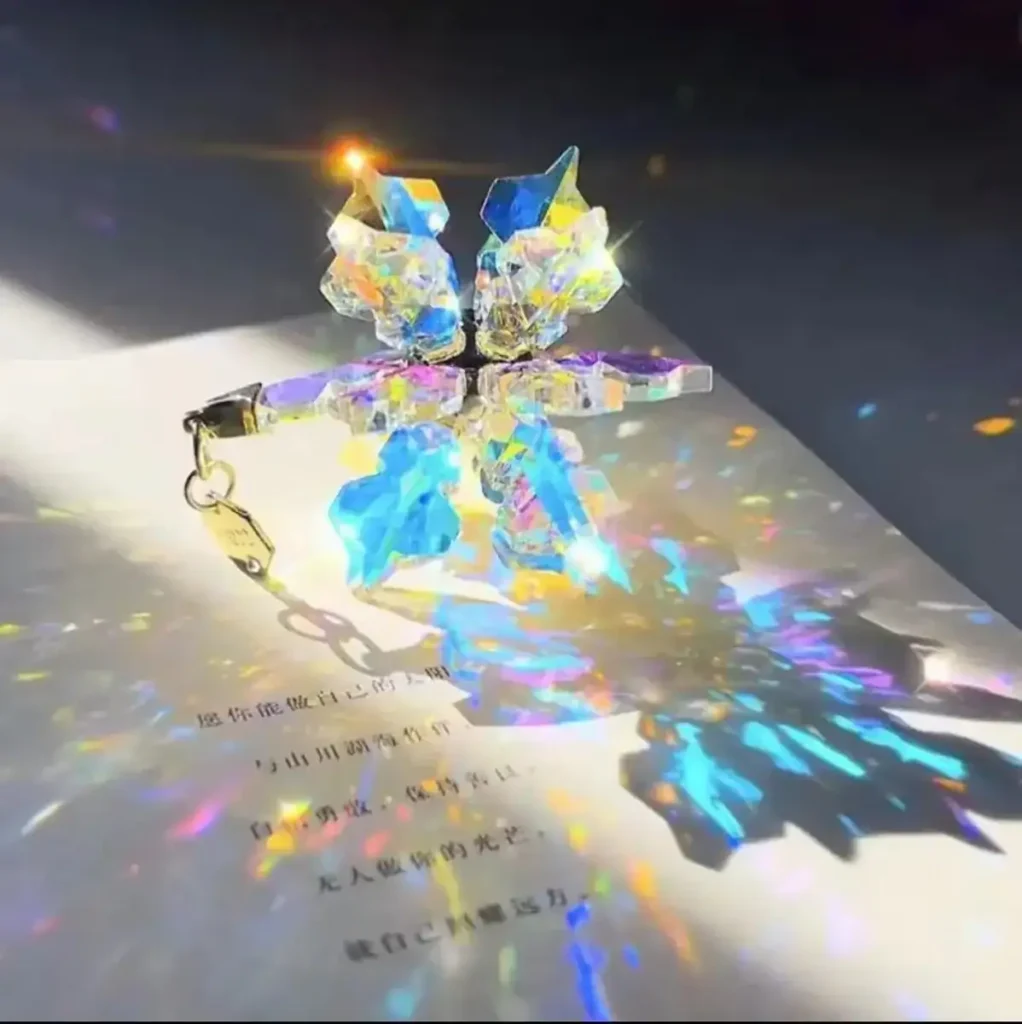 Vibrant crystal butterfly keychain casting colorful light reflections on paper.