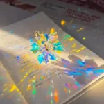 Colorful holographic star-shaped paper craft reflecting rainbow colors on a white surface, perfect for educational and decorative projects.