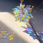 Iridescent snowflake-shaped prism crystal ornament casting colorful light reflections on a surface. Perfect for science decor and educational toys.