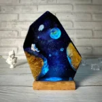 Handcrafted cosmic resin art piece featuring planets, stars, and nebulae, mounted on a wooden base, perfect for science-themed decor and educational display.