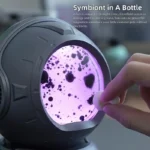 Interactive magnetic symbol in a bottle with purple liquid and floating black particles, demonstrating magnetic attraction and scientific curiosity.