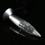 A sleek, modern science gadget resembling a metallic pen with a transparent section filled with glittering particles, set against a black background.
