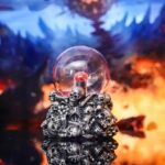 Intricate skull-themed crystal ball with a glowing red core, set against a fiery, mystical background, perfect for science decor and educational displays.