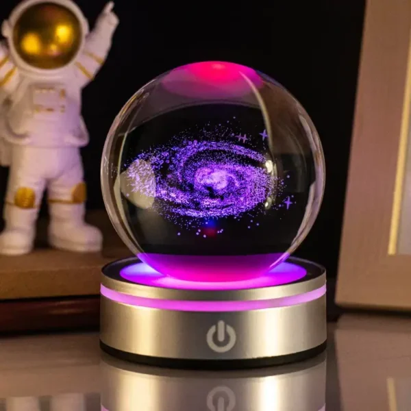 A futuristic galaxy-themed LED lamp featuring a swirling cosmic galaxy inside a glass sphere, illuminated with vibrant purple and pink lights, resting on a sleek metallic base with touch control.