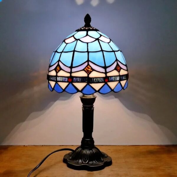 Elegant Tiffany-style stained glass table lamp featuring a colorful, intricate design and a classic black base, perfect for adding a touch of vintage charm to any space.