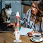 Woman working at desk with lava lamp, laptop, and coffee, accompanied by a cat, promoting stress relief and a calming workspace atmosphere.
