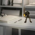 Miniature desktop spotlight with a tripod stand, illuminating a workspace.