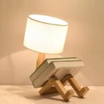 Creative book lamp with wooden legs, providing a cozy and functional lighting solution, perfect for home decor or study spaces.