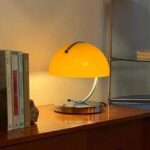 Stylish yellow desk lamp with a curved metallic arm providing warm lighting for a cozy workspace.
