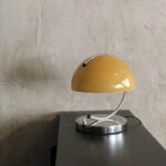 Stylish vintage-inspired desk lamp featuring a curved metal arm and a vibrant yellow shade, perfect for adding a touch of retro charm to your workspace or home decor.