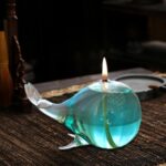 Glass whale-shaped oil lamp with a floating candle on top, creating a calming and decorative lighting piece. Perfect for home decor or educational science displays.