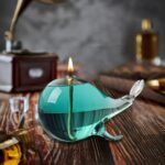 Elegant whale-shaped glass oil lamp with a teal finish, perfect for home decor and ambient lighting.