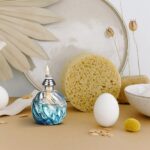 Decorative science-themed setup featuring a blue glass oil lamp, a sponge, eggs, and natural elements for educational and aesthetic purposes.