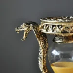 Ornate gold snake-shaped lid on a glass jar with a decorative metal rim, showcasing intricate craftsmanship and a luxurious design.