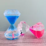 Blue, pink, and clear hourglass science toys with penguin figures, filled with vibrant liquids, ideal for educational displays and science-themed decor.