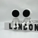 Cute astronaut figurines with large black helmets sitting on a white block with "LONDON" text.