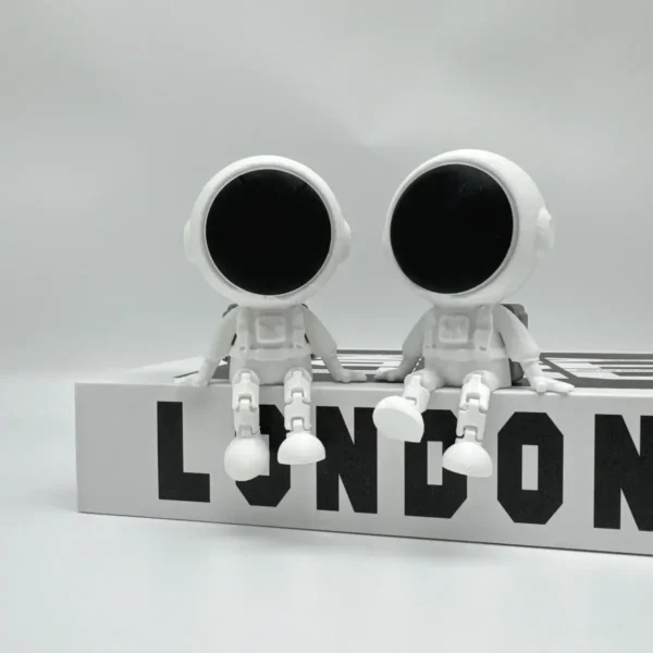 Cute astronaut figurines with large black helmets sitting on a white block with "LONDON" text.