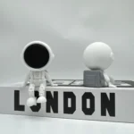 Astronaut and moon figurines with London-themed base, showcasing space exploration and celestial objects in a modern, monochrome design.