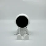 Cute white space explorer robot toy with a large black visor, sitting on a plain white background, perfect for educational and science-themed decor.