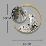 Decorative moon and astronaut wall clock with a space theme, featuring a lunar surface design and gold accents, measuring 38cm by 40cm.