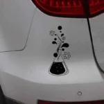 Decorative sticker of a chemistry flask with atomic symbols and scientific elements, applied on a white car surface.