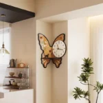 Decorative butterfly-shaped wall clock featuring floral accents and a small cat silhouette, adding a whimsical touch to home decor.