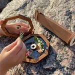 Small wooden-framed terrarium kit with tiny plants, decorative stones, and a mirror, perfect for educational and decorative purposes.