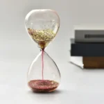 Clear sandglass timer with gold glitter, demonstrating time measurement for educational and decorative purposes.