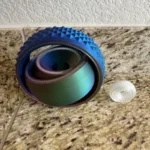 A vibrant, multi-colored 3D-printed spiral puzzle toy with textured surface, designed for educational and recreational use, placed on a granite countertop.