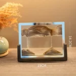 Educational sand and water erosion model demonstrating geological processes, with a glass frame measuring 14.2 cm in height and 19 cm in width, placed on a wooden surface.