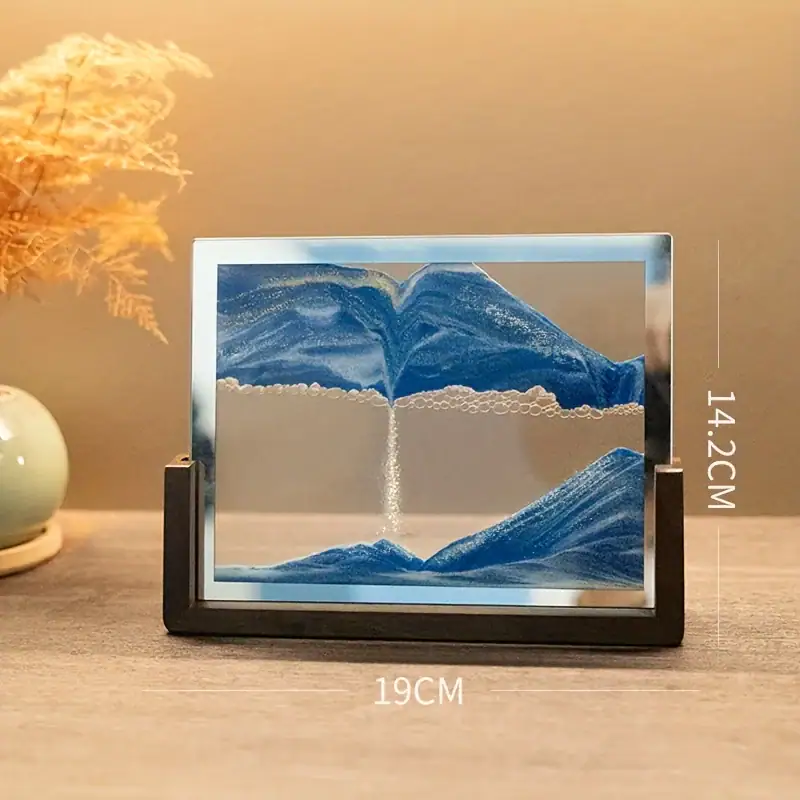 A detailed miniature mountain landscape inside a glass frame, showcasing layered blue mountains and a flowing waterfall, perfect for educational or decorative purposes.